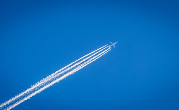 white airplane flying under the blue sky